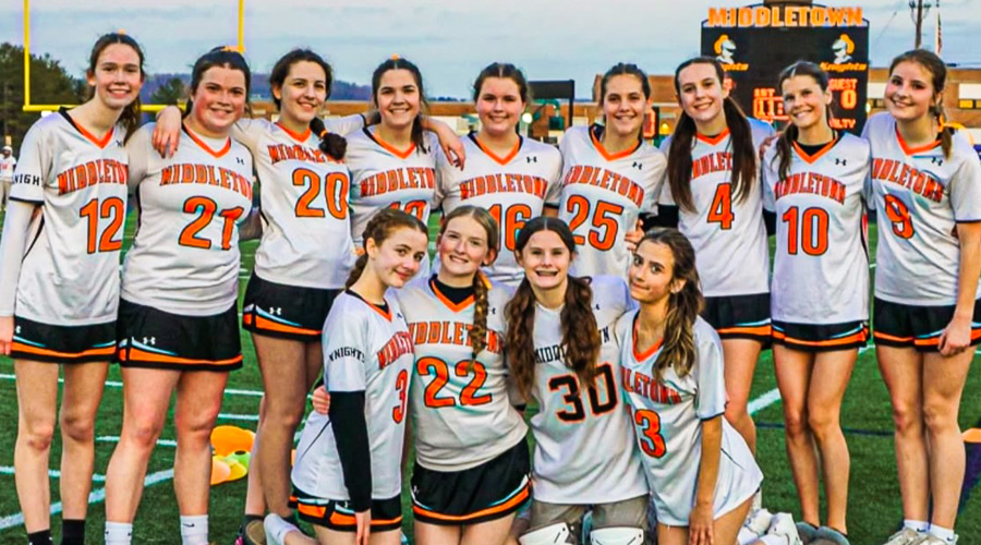 Women's Lacrosse Team sticks in the air.